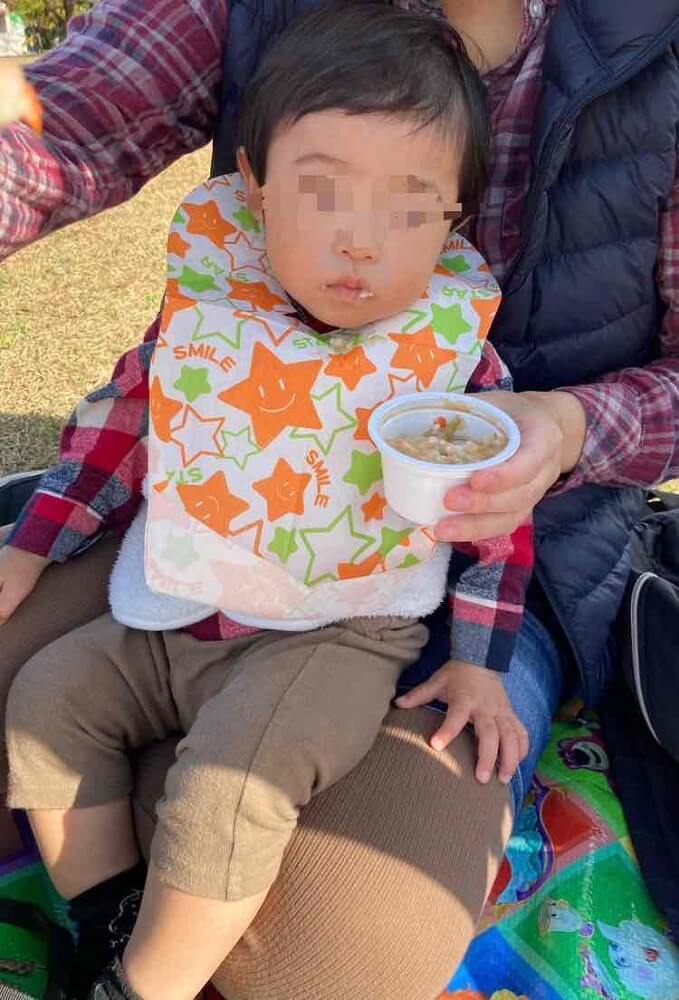 紙エプロンをしてご飯を食べる赤ちゃん